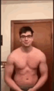 a shirtless man wearing glasses is standing in front of a door in a bathroom .