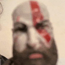 a man with a beard and blood on his face is looking at the camera .