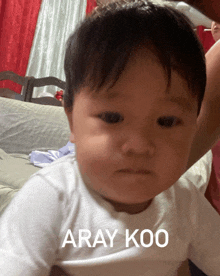a baby in a white shirt with the words aray koo on the front