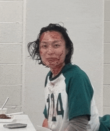 a man is sitting at a table with blood on his face .