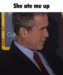a man in a suit and tie is sitting in front of a blackboard that says she ate me up .