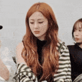 a woman with long red hair is wearing a striped sweater and a black shirt .