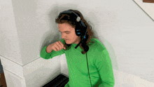 a man in a green shirt is wearing headphones with a microphone