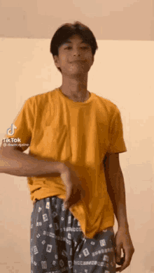a young man in a yellow t-shirt and gray pajamas is dancing .