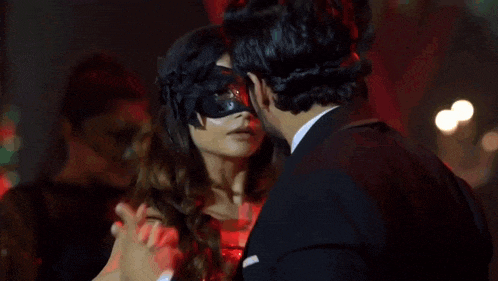 a man in a mask is dancing with a woman in a tuxedo .