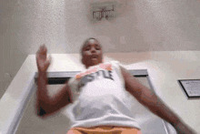 a man wearing a hustle tank top is standing in front of a door