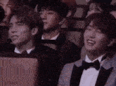 a group of people are sitting in a theatre and one of them is wearing a bow tie .