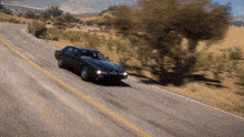 a black car is driving down a road with a yellow line