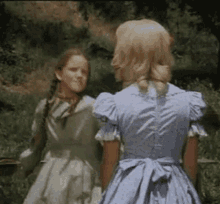 two girls in dresses are standing next to each other in the grass .