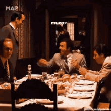 a group of men are sitting at a table with plates and glasses .