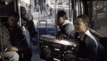 a group of people are sitting on a bus with a boombox