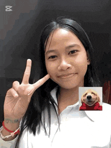 a girl giving a peace sign with a picture of a dog in the background
