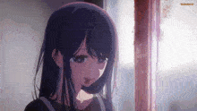 a girl with long black hair is standing in front of a window and looking out .