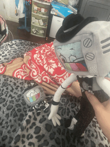 a person is holding a stuffed toy that looks like a tv with a hat on