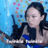 a woman is playing a guitar and singing into a microphone with the words twinkle twinkle below her