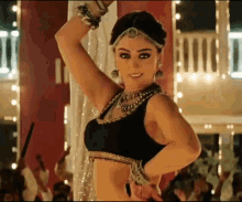 a woman in a black top and gold jewelry is dancing in a room .