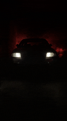 a car is lit up in the dark with a red background