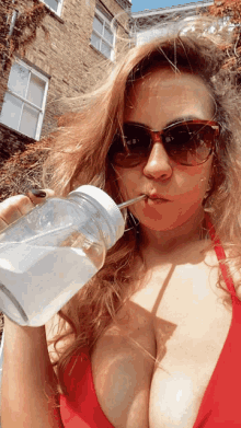 a woman in a red bikini drinks from a mason jar with a straw