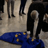 a man is laying a blue flag with yellow stars on it on the floor