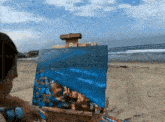 a man is painting a picture on the beach