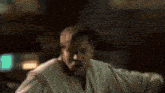 a man in a robe is laying on a bed and looking at the camera .