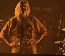 a woman singing into a microphone while wearing a jersey that says t on it