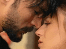a man with a beard kisses a woman on the nose