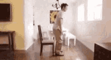 a man is standing in a living room next to a dining room table and chairs .