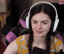a woman wearing headphones sits in a chair with a daily sign in the background