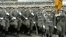 a large group of soldiers marching in a parade with guns and helmets .