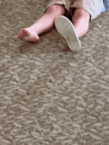 a baby is laying on the floor with a pair of converse shoes on his feet