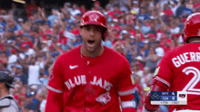 a baseball player wearing a red blue jays jersey celebrates