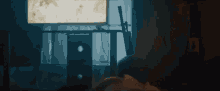 a person is sitting in front of a window in a dark room