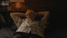an older man is laying on a bed with his hands behind his head and the words son of a glitch on the bottom