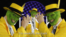 three men wearing green masks and yellow jackets are smoking the track