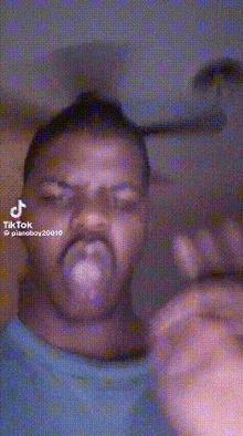 a man with a bun on his head is making a funny face and pointing at the camera .