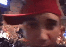 a man wearing a red hat is standing in front of a crowd .