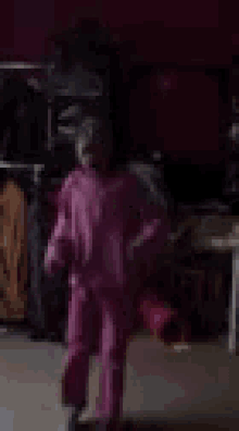a little girl in a purple pajama set is standing in a room .