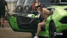 a man is sitting in a green sports car with showtime written on the bottom