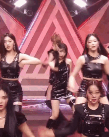 a group of women are dancing on a stage with a red background .