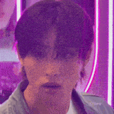 a close up of a young man 's face with purple hair and a purple background .