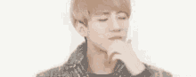 a close up of a young man making a face with his hand on his face .
