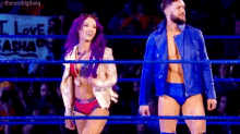 a man and a woman are standing in a wrestling ring together .