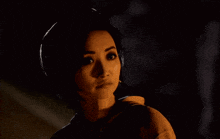 a woman in a dark room looks at the camera