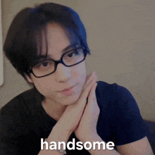 a person wearing glasses and a black shirt with the word handsome written on it