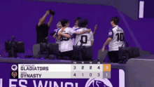 a group of people hugging each other in front of a scoreboard that says los angeles gladiator