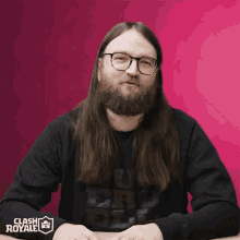 a man with long hair and a beard is wearing glasses and a black shirt that says clash royale