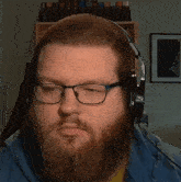 a bearded man wearing glasses and headphones looks at the camera