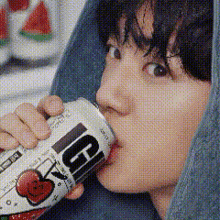 a close up of a person drinking from a can with the letter g on it
