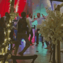 a group of people are standing in a room with trees in the foreground
